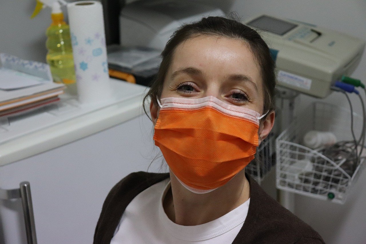 A nurse sporting a smile behind an orange surgical mask