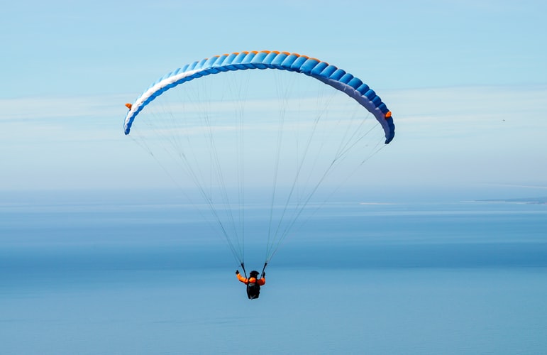 A person paragliding under the blue sky