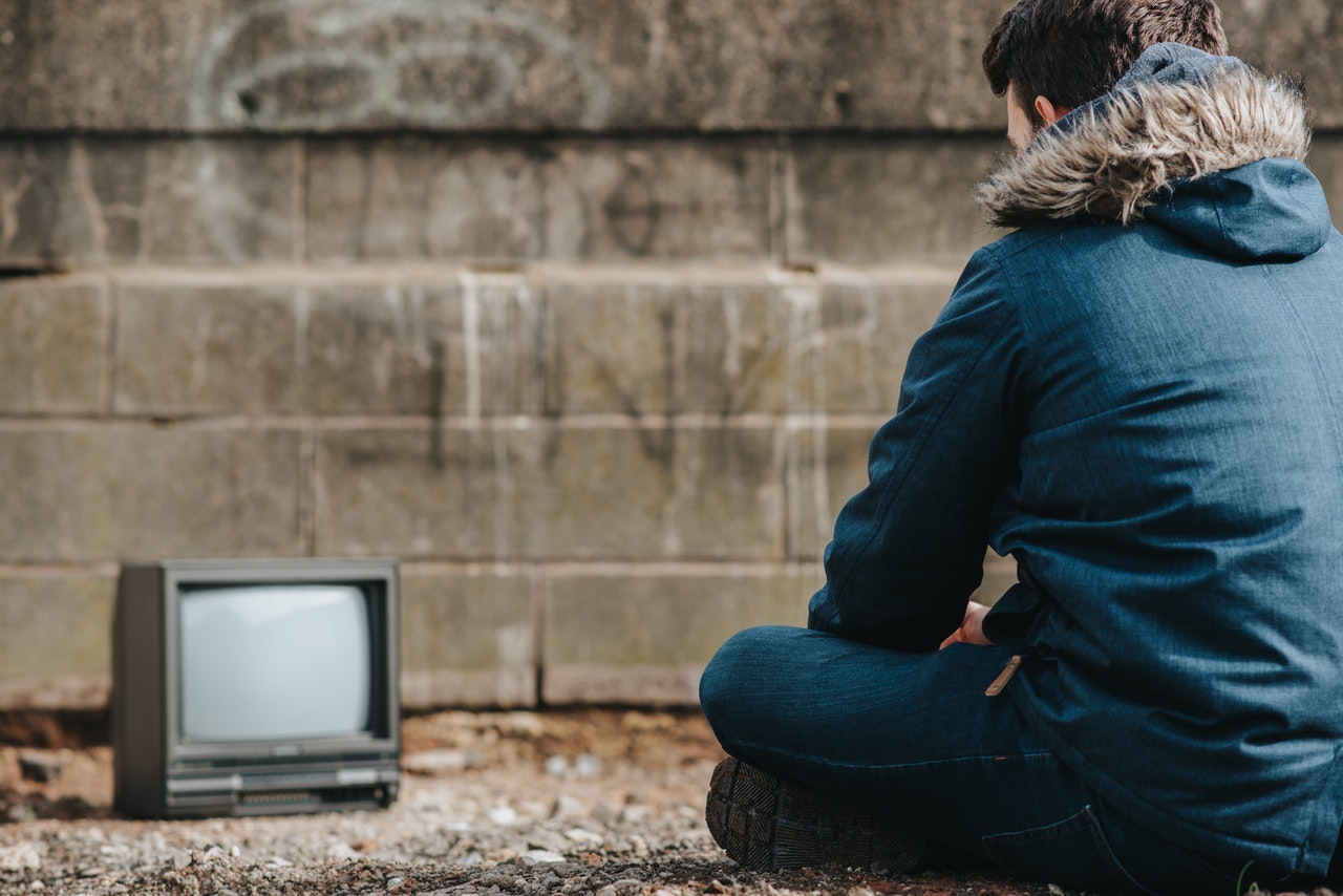 A man sitting on the ground in front of an small old tv