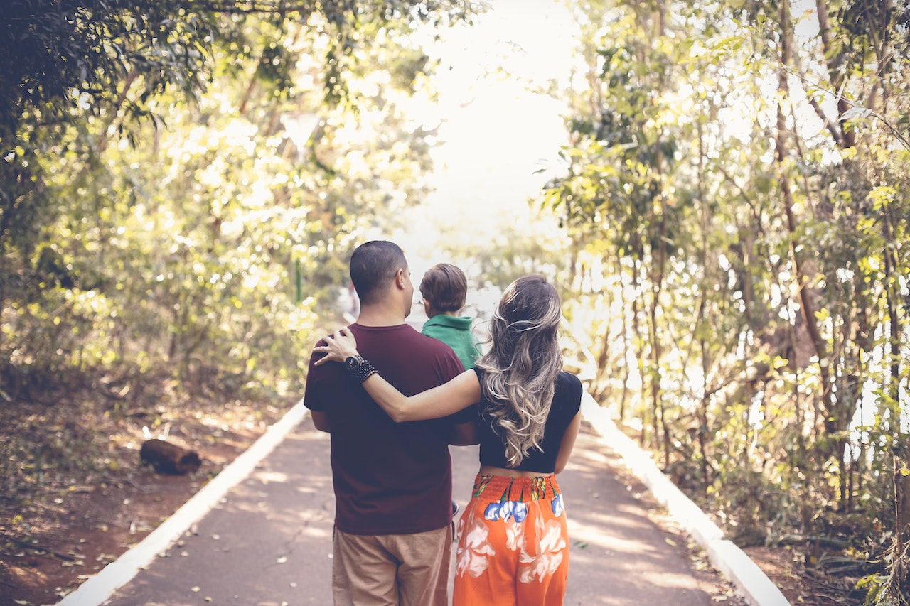 A couple with a child walking on a path amidst trees